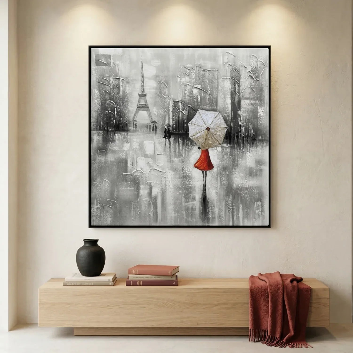 Framed artwork of a cityscape with Eiffel Tower and person with umbrella on a wall above a wooden console table.